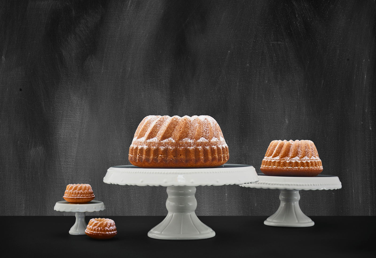 Drei Tortenplatten in verschiedenen Größen mit Gugelhupf-Kuchen, seitliche Perspektive