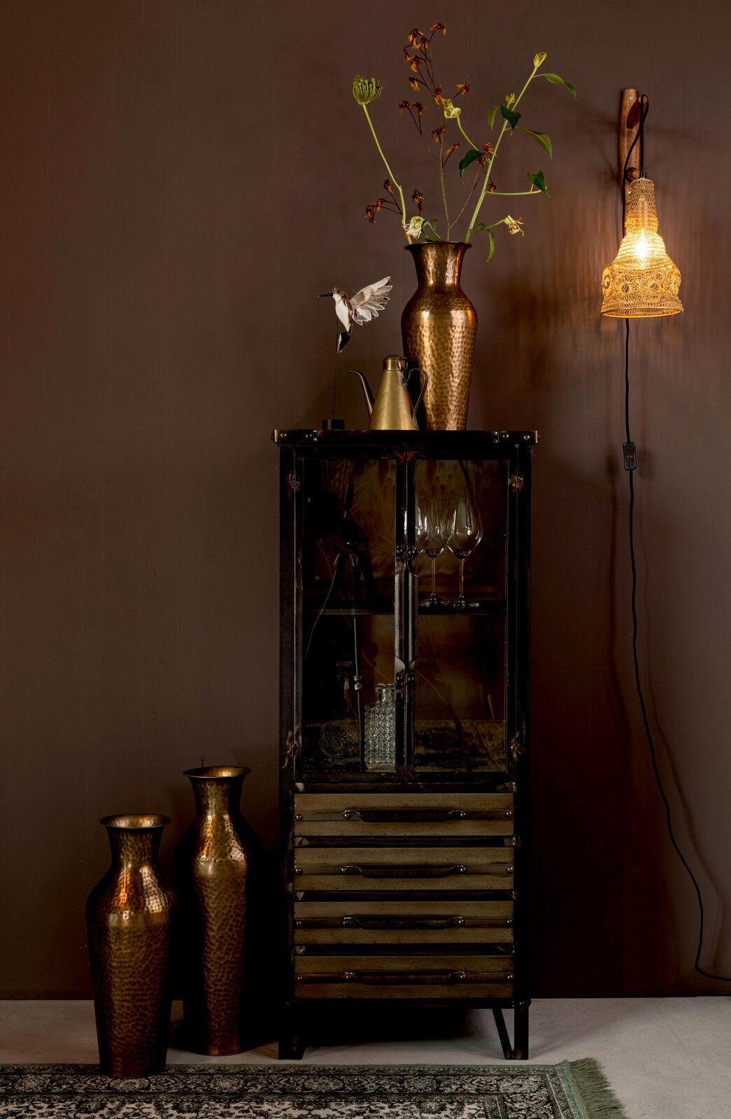 Hochwertiges Highboard mit Glasfront und Schubladen, dekoriert mit Vasen und einer Lampe, seitliche Perspektive