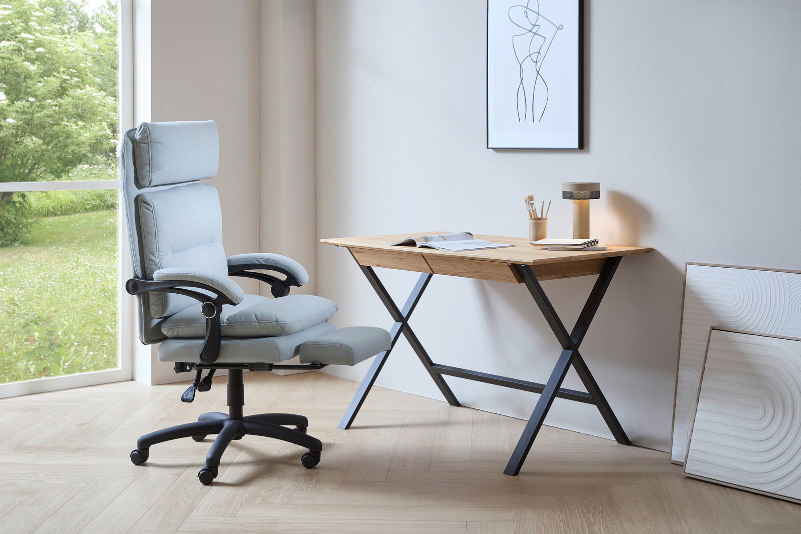 Moderner Schreibtisch mit Holzplatte und schwarzen Metallbeinen, seitliche Perspektive. Daneben ein ergonomischer Bürostuhl vor einem großen Fenster mit Blick ins Grüne.