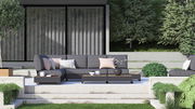 Moderne Gartenmöbel-Lounge mit grauem 3-Sitzer-Sofa, Kaffeetisch und Kissen, umgeben von grüner Landschaft, frontale Perspektive