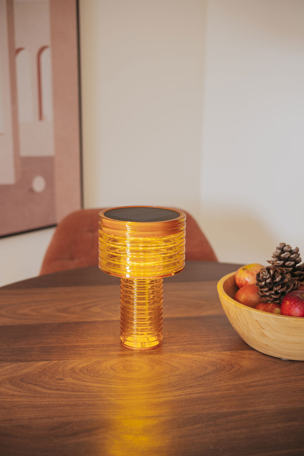 Akku-Solar-Tischleuchte in warmem Licht auf einem Holztisch, seitliche Perspektive