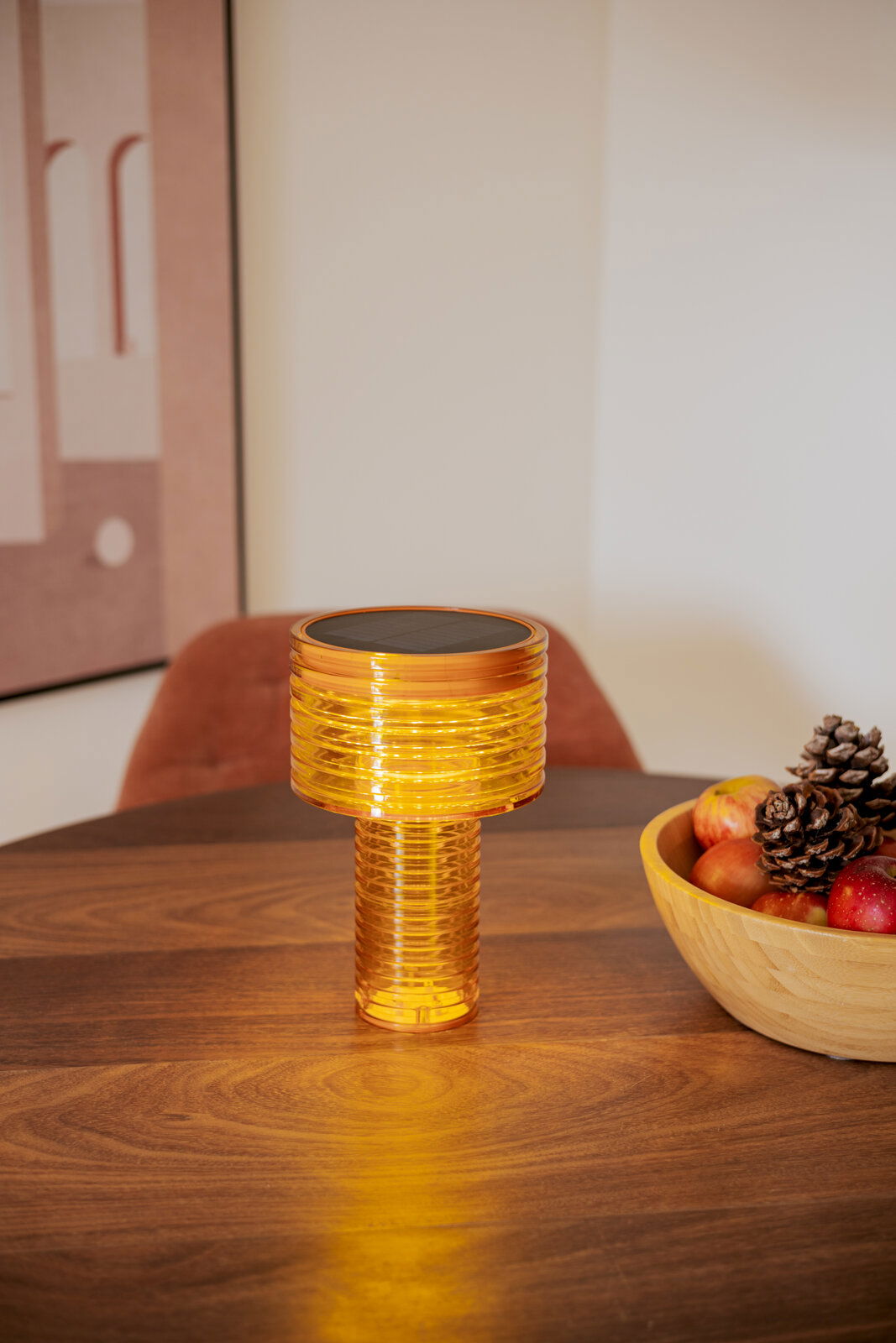 Akku-Solar-Tischleuchte in warmem Licht auf einem Holztisch, seitliche Perspektive