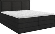 Donkergrijs gestoffeerd tweepersoons boxspringbed met hoog, verticaal gestikt hoofdbord en witte gewatteerde topmatras, schuin van voren weergegeven.
