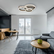 Moderne Deckenleuchte mit mehreren ineinander verschlungenen Ringen, von unten betrachtet in einem stilvollen Wohnzimmer.