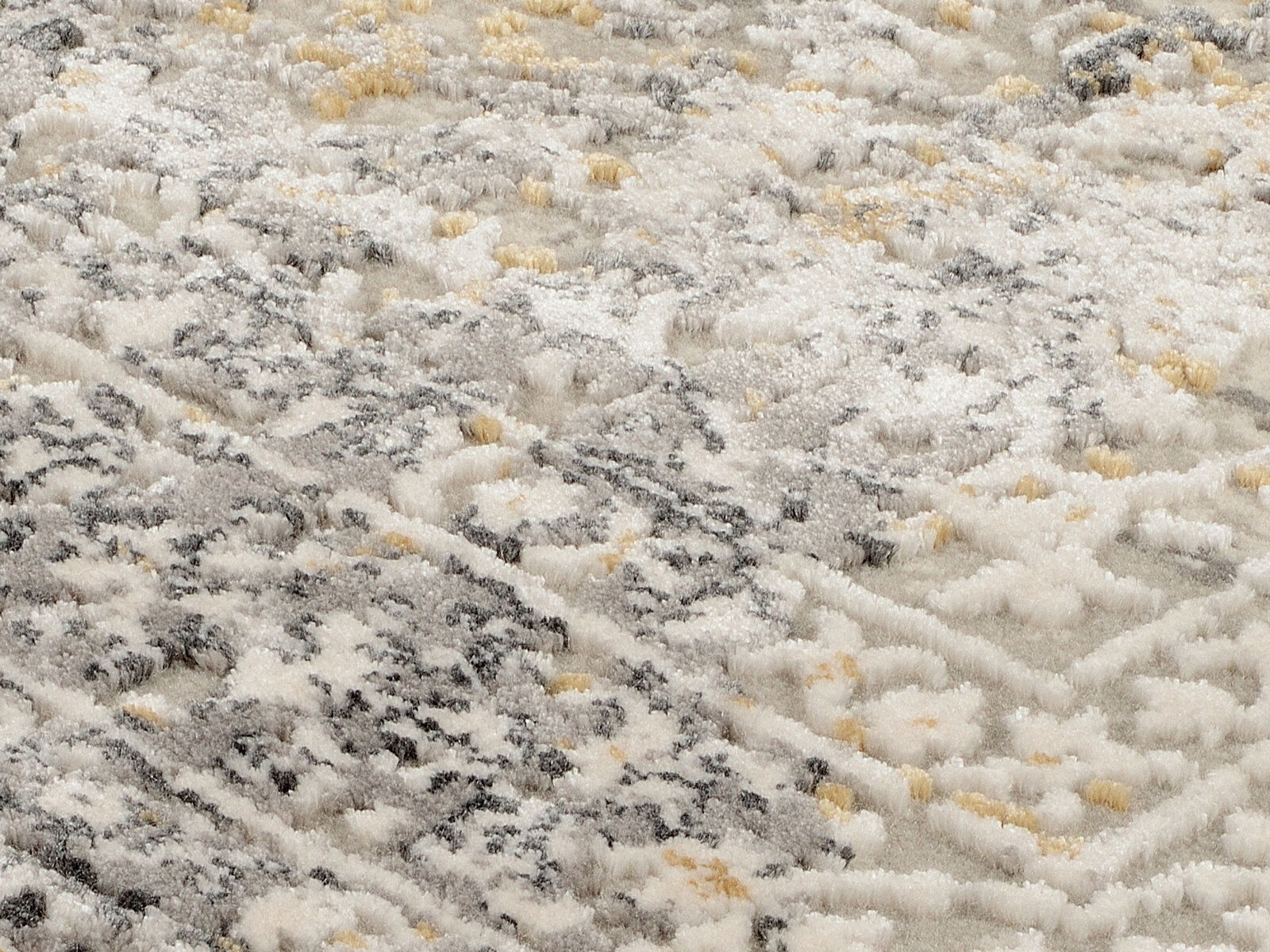 Nahaufnahme eines Designer-Teppichs mit grauen, weißen und beigen Mustern in diagonaler Perspektive.