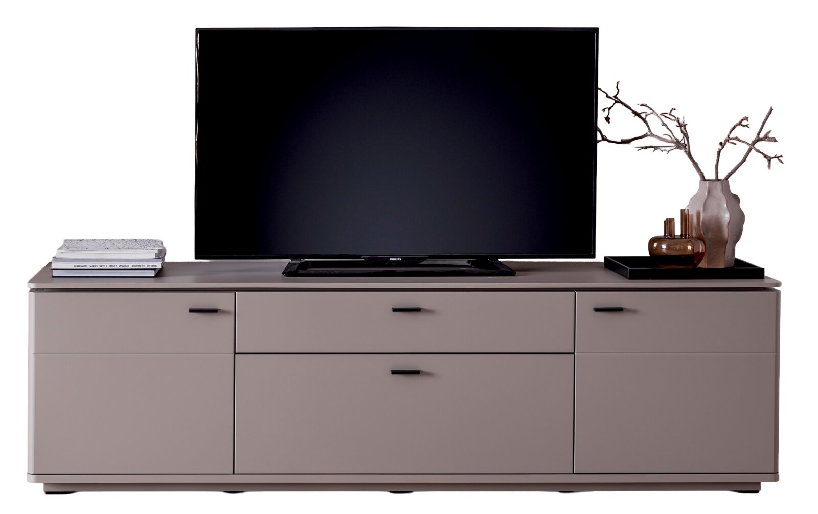 Zurbrüggen Tv-kast TORRENT Modern tv-lowboard in taupe/grijs met lades en deuren, met daarop een grote flatscreen-tv en decoratie (een stapel boeken en een vaas met takjes), vooraanzicht