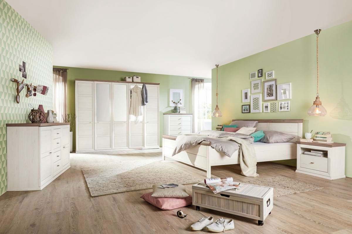 Schlafzimmer mit einem 5-türigen Drehtürenschrank CAMRON in heller Holzoptik, umgeben von weiteren Möbeln in einem modern eingerichteten Raum mit grüner Wandfarbe. Perspektive: Frontalansicht des Schranks.