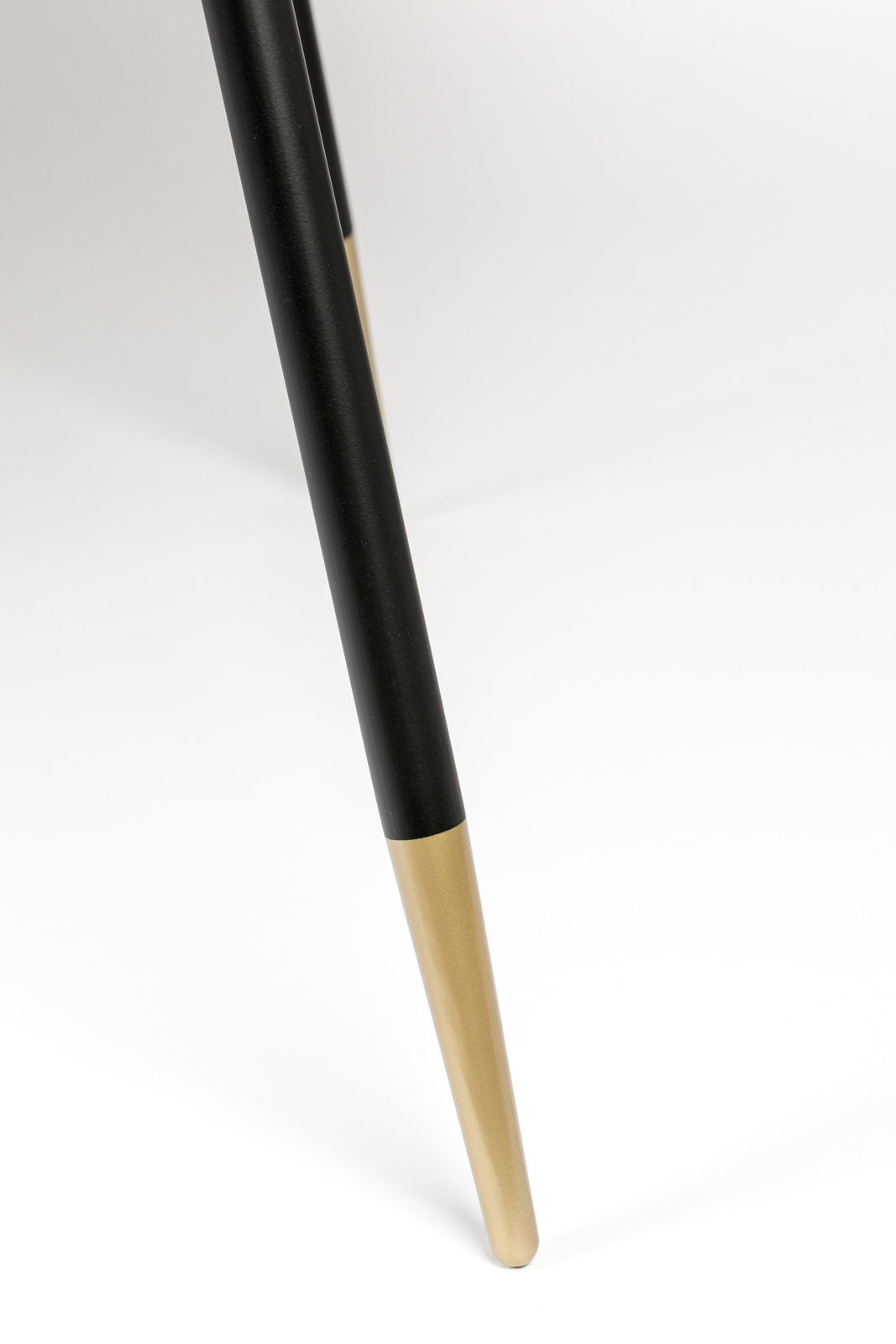 Nahaufnahme eines Tischbeins mit schwarzer und goldener Farbgebung, schräg von der Seite fotografiert.