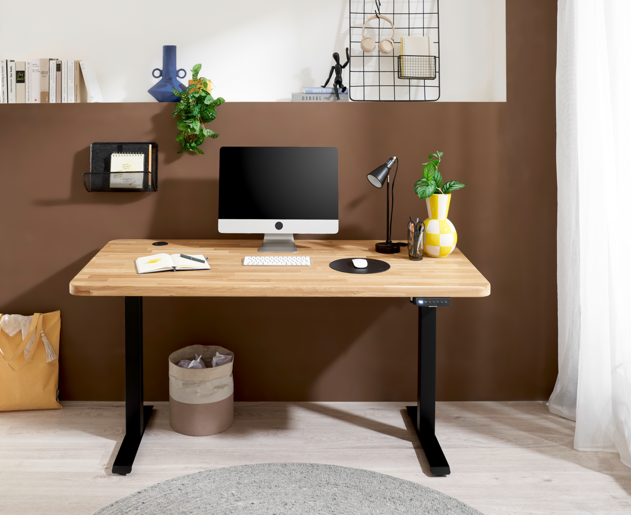 Moderner E-Schreibtisch aus Holz mit schwarzem Gestell, frontal fotografiert, ausgestattet mit Computer, Lampe und Dekoration.