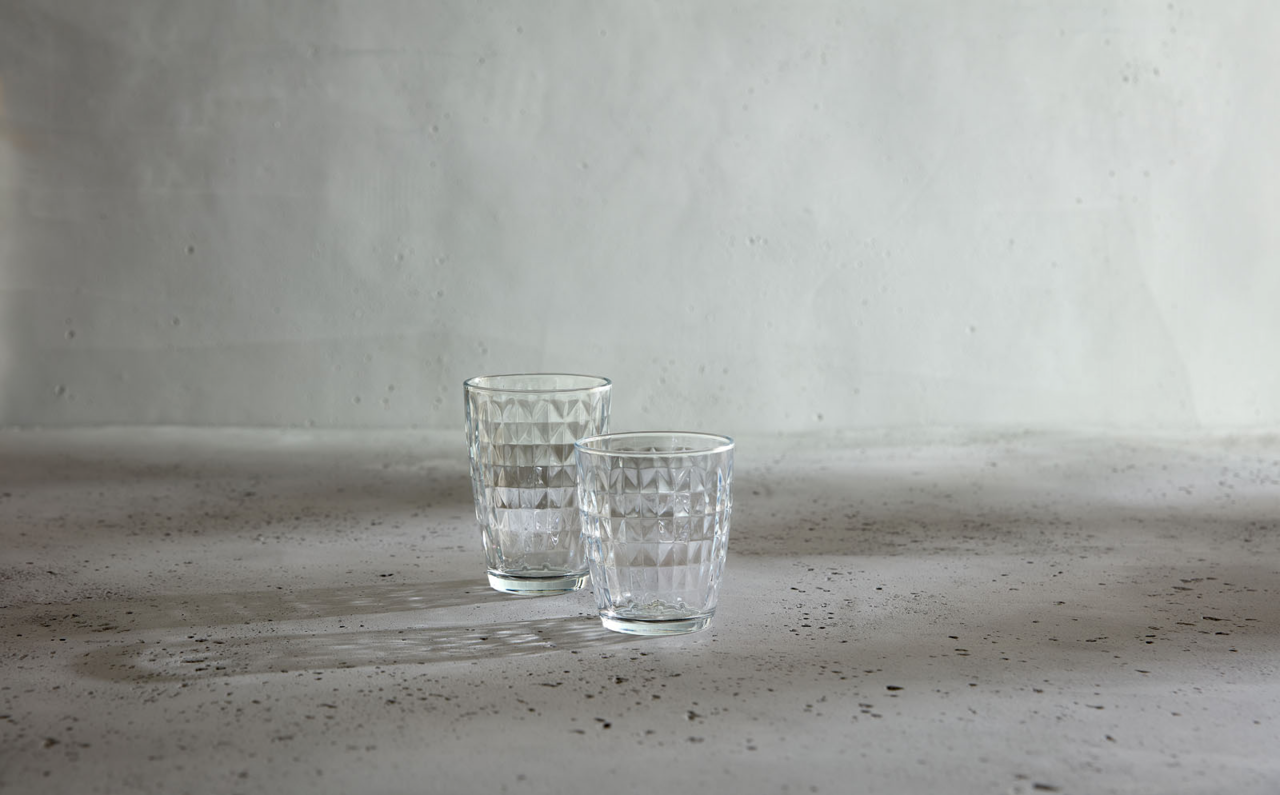 Zwei Gläser mit geometrischem Muster auf einer Betonoberfläche, seitliche Perspektive.