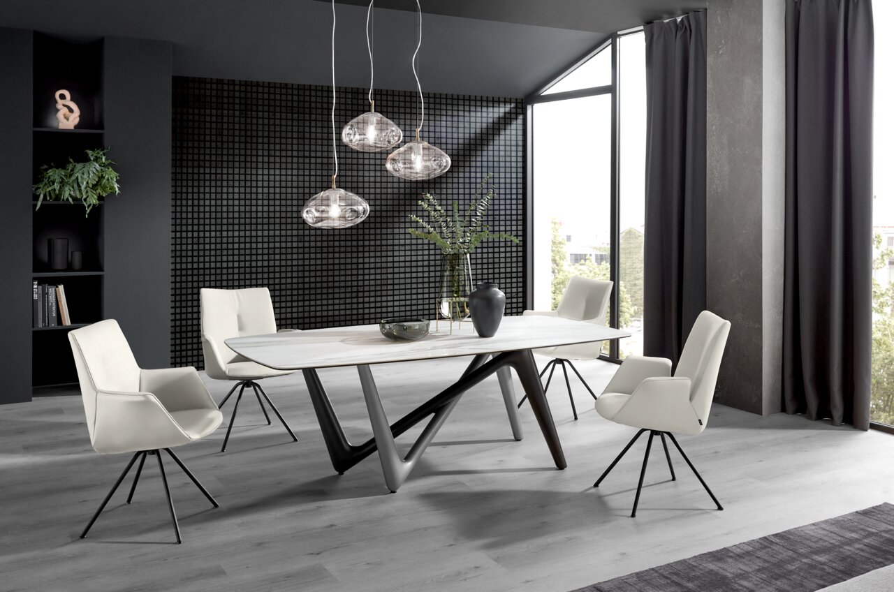 Moderner Essbereich mit vier weißen Sesseln um einen eleganten Tisch, seitliche Perspektive.