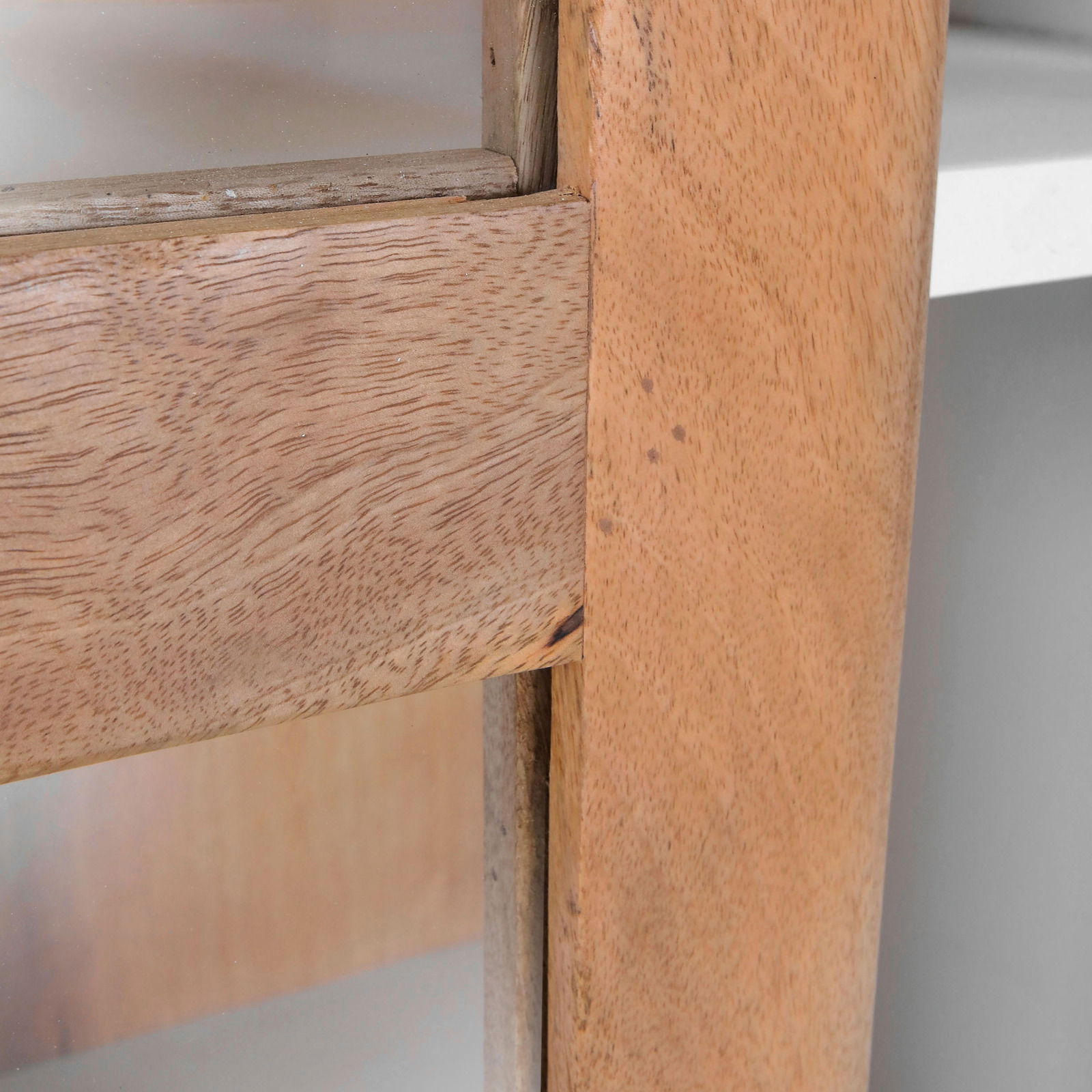 Nahaufnahme einer Vitrine aus hellem Holz mit Glasfront, seitliche Perspektive.