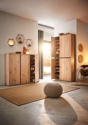 Schuhschrank aus Holz in einem modernen Wohnzimmer, mit geöffneter Tür, die mehrere Regale mit Schuhen zeigt. Perspektive von vorne links.