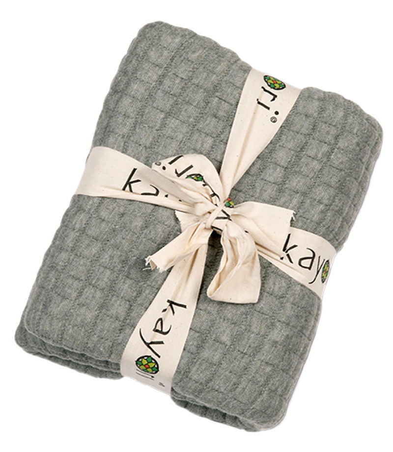 Kayori Plaid MOFU Graues Plaid 150x220cm, gefaltet und mit einem bedruckten Band zusammengebunden, aus der Vogelperspektive fotografiert.