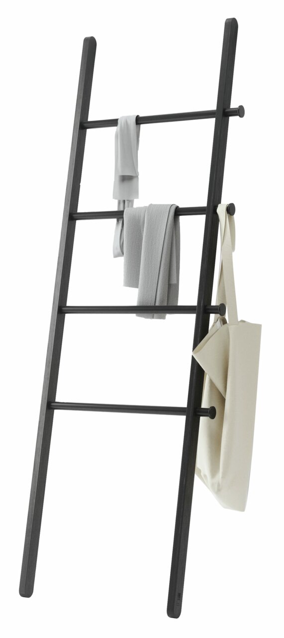 Schwarze Anlehnleiter mit mehreren Sprossen, auf denen Handtücher und eine Tasche hängen. Perspektive von der Seite.