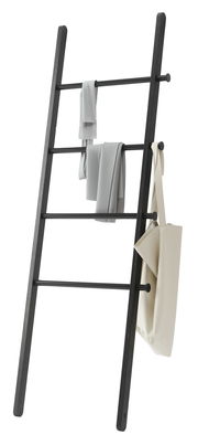 Schwarze Anlehnleiter mit mehreren Sprossen, auf denen Handtücher und eine Tasche hängen. Perspektive von der Seite.