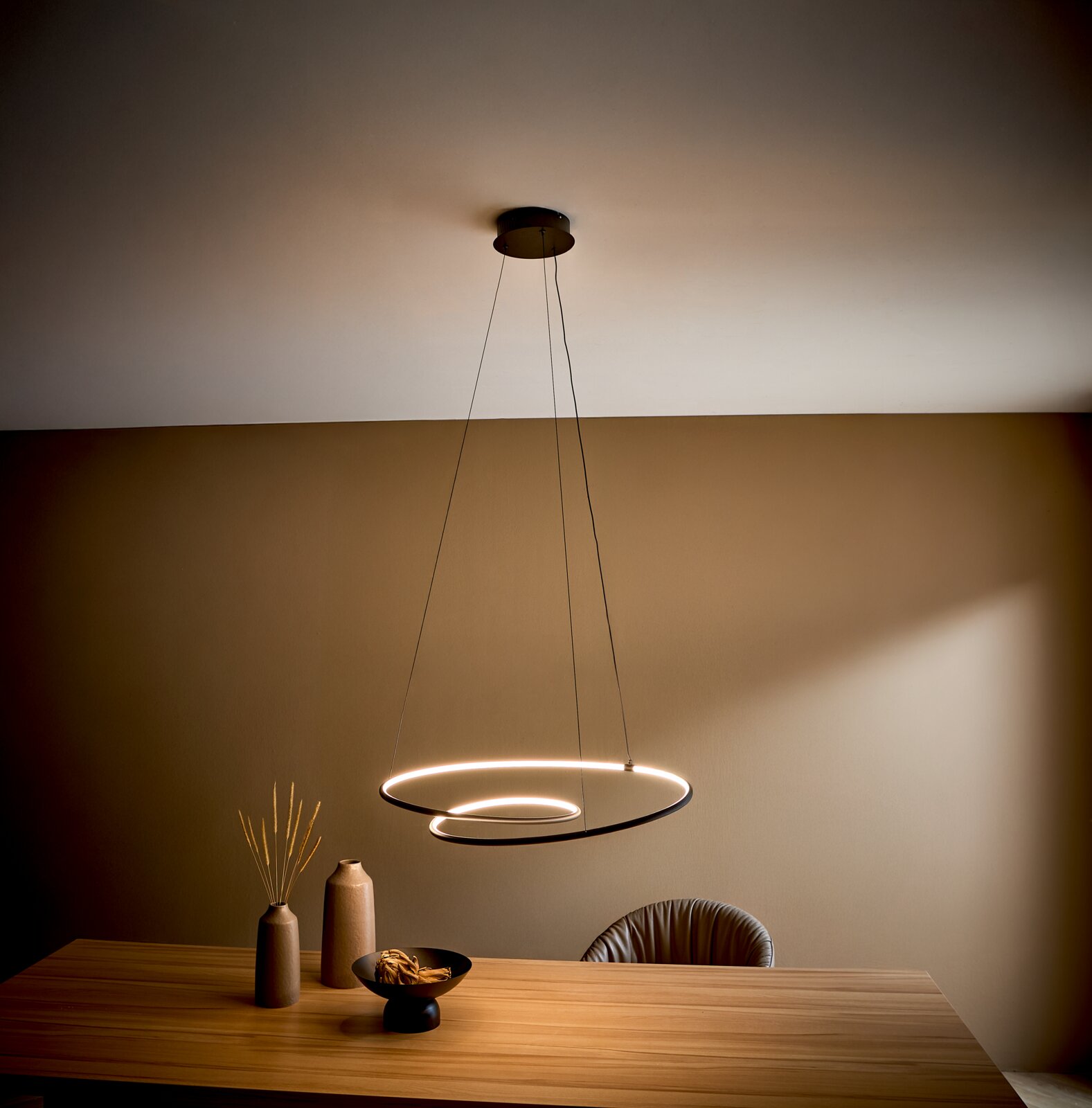 Novel LED-Hängeleuchte BIRMINGHAM Moderne LED-Pendelleuchte mit zwei schwebenden, ringförmigen Lichtkreisen über einem Holztisch im Esszimmer, aufgenommen aus leicht niedriger Perspektive nach oben (Untersicht).