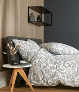 Bettwäsche-Set in elegantem Paisley-Muster auf einem Bett, seitliche Perspektive, mit einem modernen Nachttisch und Dekoration im Hintergrund.