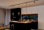 Moderne Küche mit drei hängenden Dekoschirmen Biraha in einem eleganten, minimalistischen Design. Perspektive von der Seite, die die gesamte Kücheninsel und die Hängelampen zeigt.