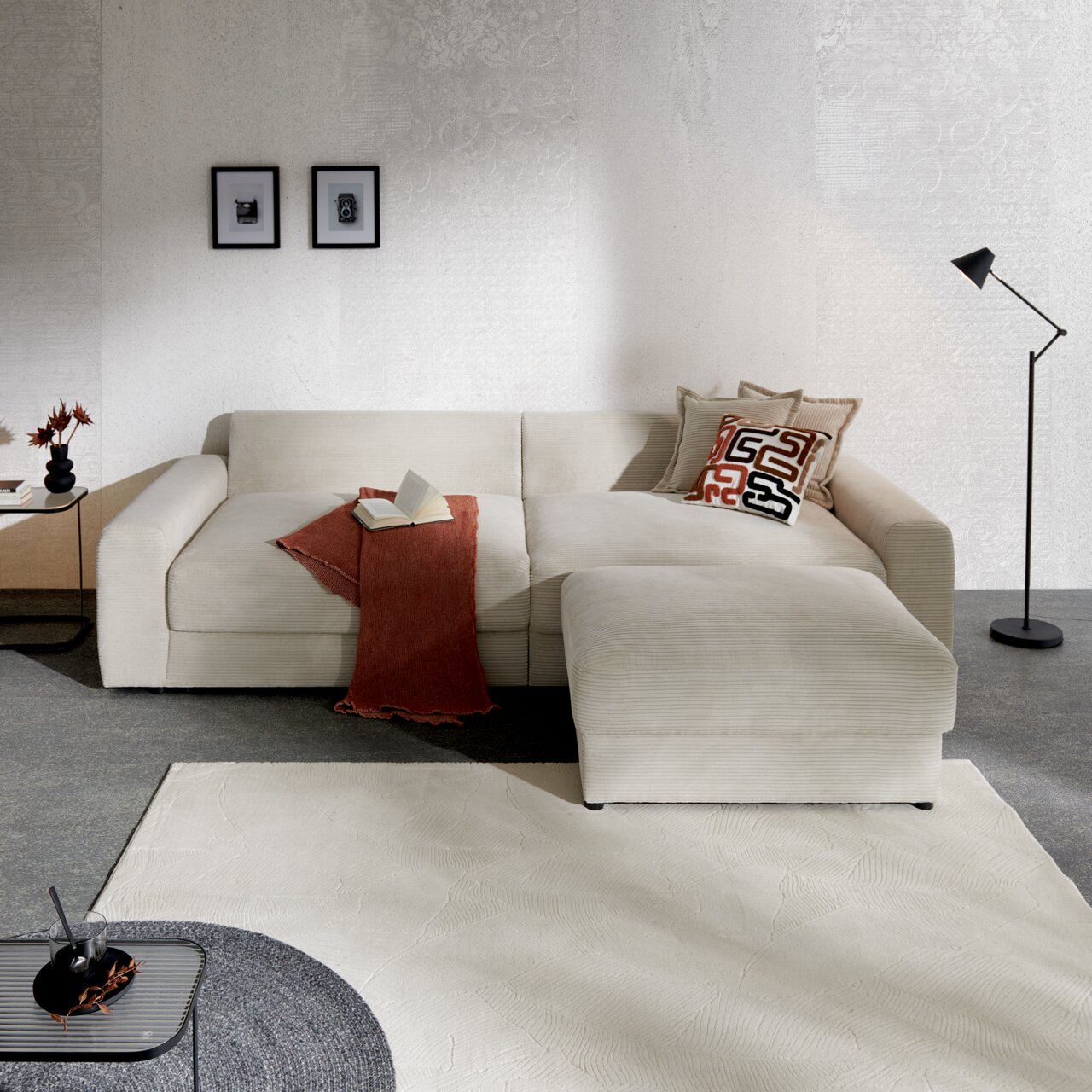 Z2 Hocker Napoli Beige Ecksofa in einem modernen Wohnzimmer, seitliche Perspektive, mit Kissen und einer Decke dekoriert.