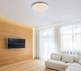 Moderne Deckenleuchte DORO in einem stilvollen Wohnzimmer, von unten betrachtet, mit Holzverkleidung und großen Fenstern im Hintergrund.