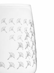 Nahaufnahme eines Weißweinglases mit mattem, dekorativem Muster auf der Oberfläche, seitliche Perspektive.