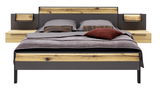 Modernes Doppelbett mit Holz- und Metallelementen, frontal fotografiert, mit grauer Bettwäsche und dekorativen Kissen.
