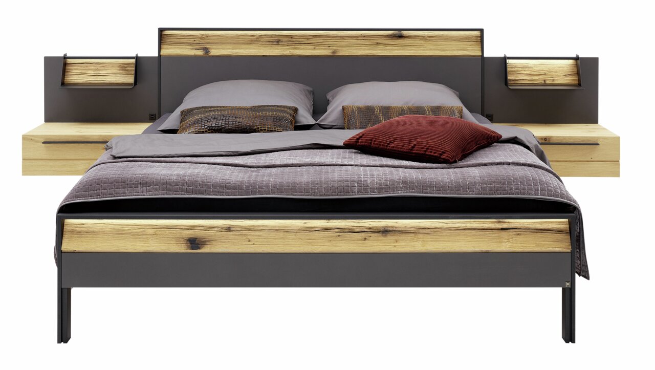 Modern tweepersoonsbed met houten en metalen elementen, gefotografeerd van voren, met grijs beddengoed en sierkussens.