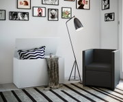 Schwarze Stehlampe mit schlankem Dreibein-Stativ und konischem Schirm neben grauem Sessel und weißer Aufbewahrungsbox in modernem Wohnzimmer, Perspektive: leicht seitliche Frontansicht.