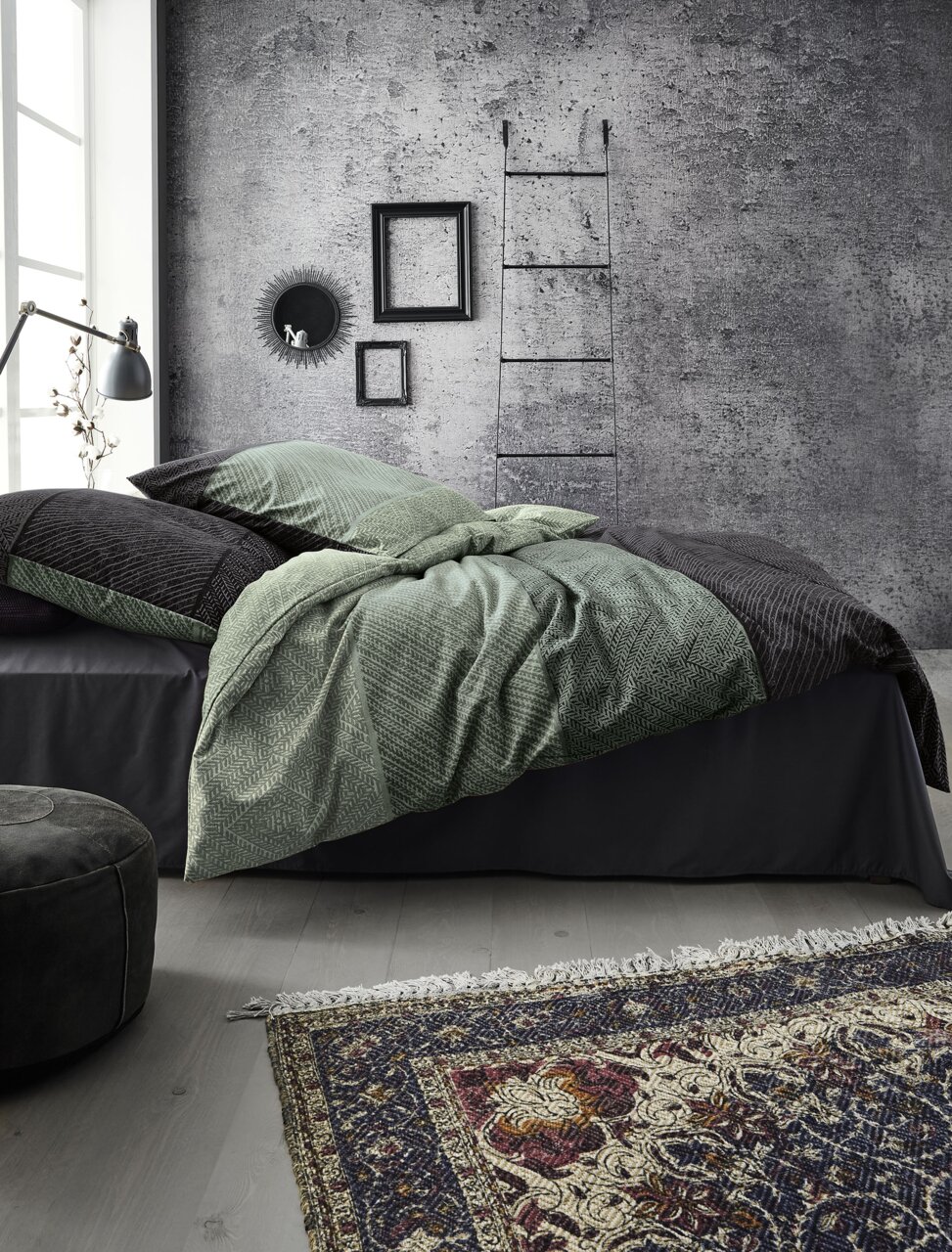 Moderne Schlafzimmeransicht mit stilvoller Bettwäsche in Grün- und Grautönen, dekoriert mit Leiter und Wandbildern im Hintergrund.