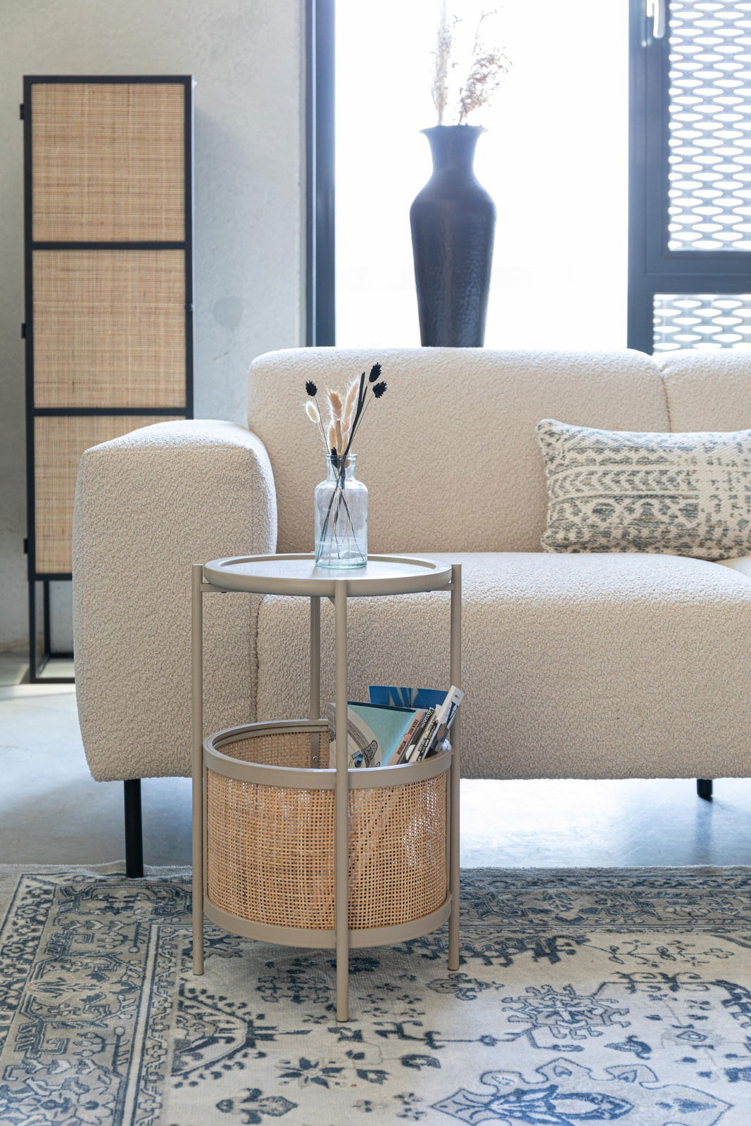 Beistelltisch mit rundem Tablett und Korb, seitliche Perspektive, neben einem Sofa in einem modernen Wohnzimmer.