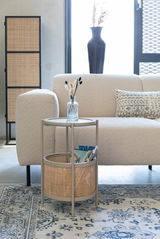 Beistelltisch mit rundem Tablett und Korb, seitliche Perspektive, neben einem Sofa in einem modernen Wohnzimmer.