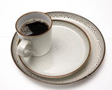 Kombiservice Visby 16-tlg. in Grau, bestehend aus einer Tasse mit schwarzem Kaffee, einem kleinen Teller und einem großen Teller, aus der Vogelperspektive fotografiert.