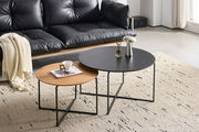 Zwei runde Couchtische im Set, einer mit schwarzer Tischplatte und der andere mit Holzoptik, auf einem hellen Teppich vor einem schwarzen Ledersofa. Perspektive von schräg oben.