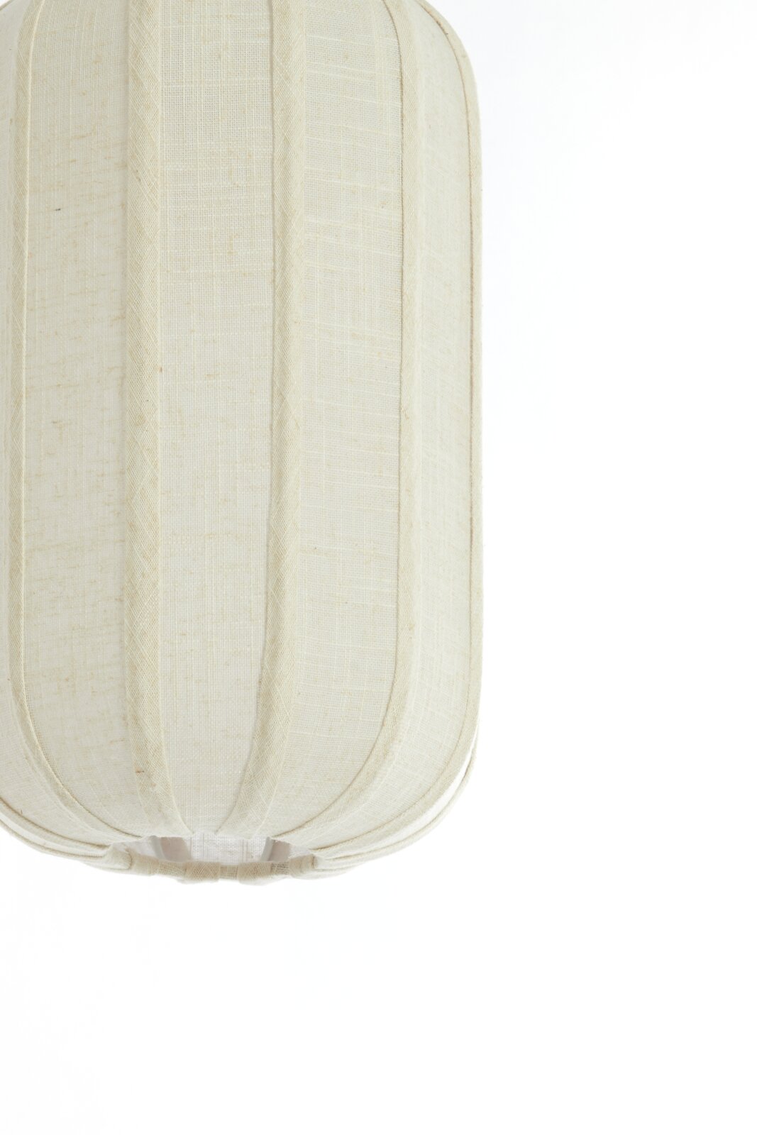 Close-up van een crèmekleurige stoffen hanglamp met verticale naden, gezien vanaf de zijkant.