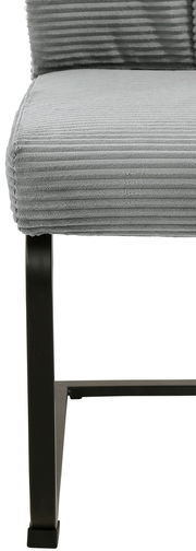 Nahaufnahme eines grauen Schwingstuhls mit geripptem Stoffbezug und schwarzem Metallgestell, seitliche Perspektive