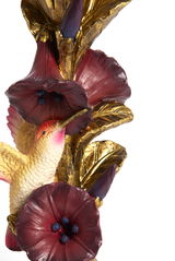 Detailansicht eines kunstvollen Kerzenständers mit goldenen Blättern, roten Blüten und einem dekorativen Vogel.
