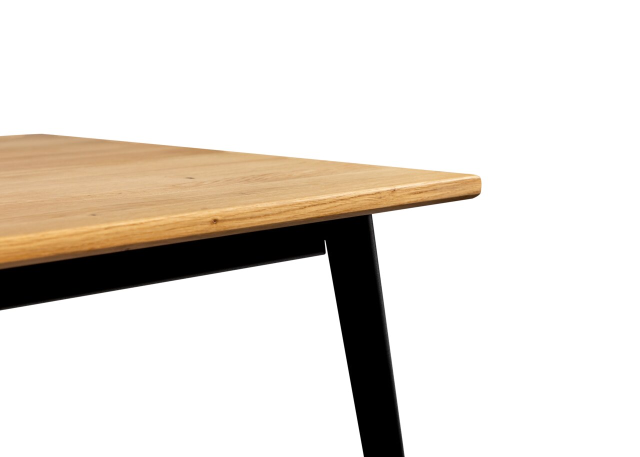 Nahaufnahme eines Esstisches mit Holzplatte und schwarzen Metallbeinen, seitliche Perspektive.