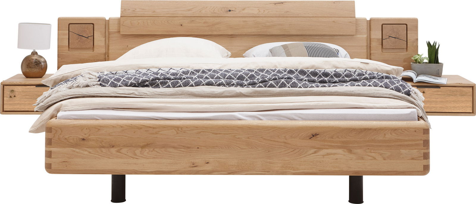 Frontale Ansicht eines modernen Bettgestells aus Holz mit integrierten Nachttischen, dekoriert mit Kissen, Decken und einer Lampe.