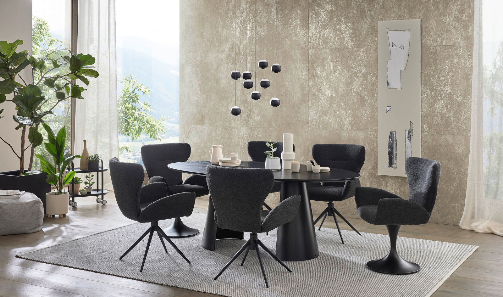 Moderner Essbereich mit einem runden, schwarzen Esstisch und mehreren schwarzen Armlehnstühlen auf einem hellen Teppich. Die Perspektive zeigt den Raum von der Seite mit Blick auf die Tischgruppe und die umgebende Dekoration.