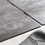Nahaufnahme eines modernen Esstisches mit grauer, strukturierter Oberfläche und einer eleganten Kante, aus der Vogelperspektive.