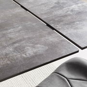 Nahaufnahme eines modernen Esstisches mit grauer, strukturierter Oberfläche und einer eleganten Kante, aus der Vogelperspektive.