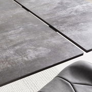 Nahaufnahme eines modernen Esstisches mit grauer, strukturierter Oberfläche und einer eleganten Kante, aus der Vogelperspektive.