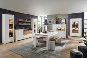 Moderne Wohnzimmermöbel in heller Holzoptik mit Vitrinen, Sideboard, Esstisch und Bank, seitliche Perspektive
