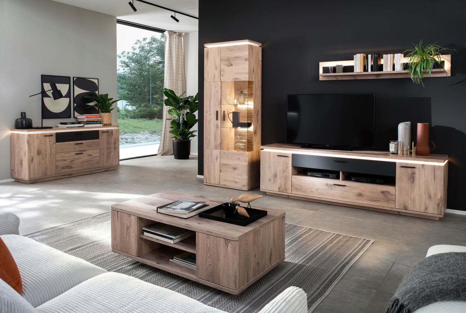 Moderne Wohnzimmermöbel in Holzoptik mit LED-Beleuchtung, bestehend aus Sideboard, Couchtisch und TV-Wand, aus der Perspektive eines gemütlichen Wohnzimmers.