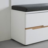 Weiße Bank mit grauem Sitzkissen, seitliche Perspektive, zeigt Schubladen mit Holzdetails.