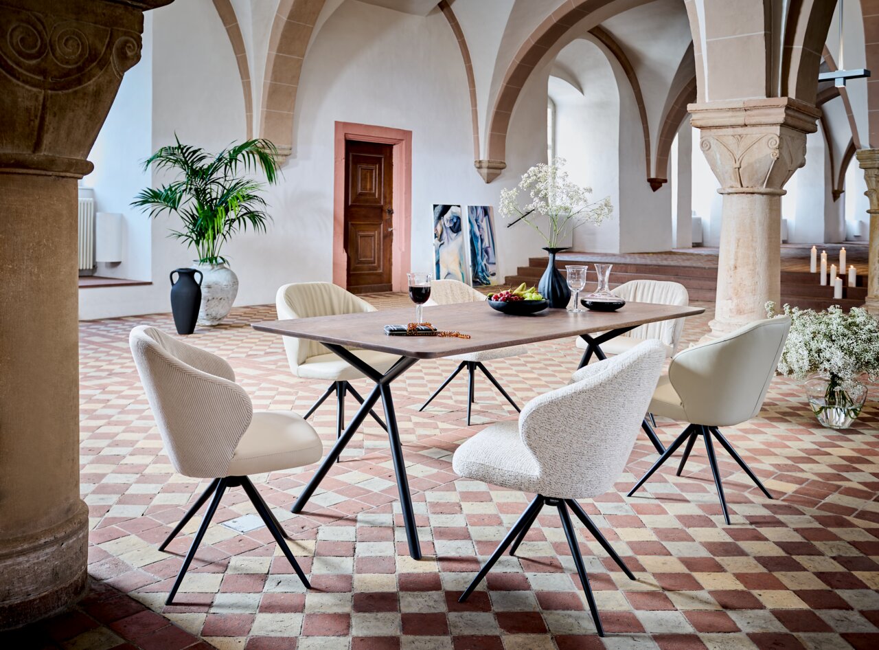 Dieter Knoll Esstisch ROXY Moderner Esstisch mit sechs Armlehnstühlen in einem eleganten Raum mit Gewölbedecke, seitliche Perspektive.