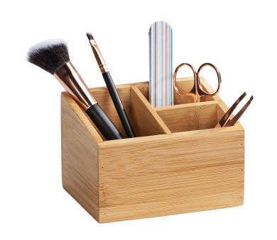 Bambus Organizer mit drei Fächern, gefüllt mit Kosmetikpinseln, Schere und Feile, aus schräger Perspektive fotografiert.