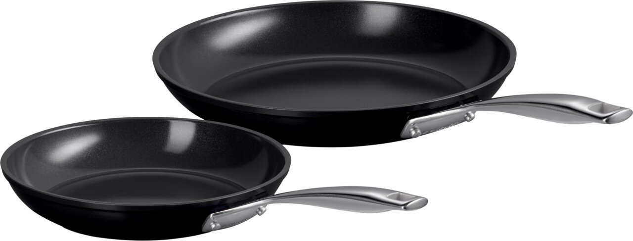 LE CREUSET Pfannenset 2-tlg. 24cm + 28cm ESSENTIAL Zwei schwarze Pfannen mit silbernen Griffen, eine kleinere und eine größere, aus seitlicher Perspektive fotografiert.