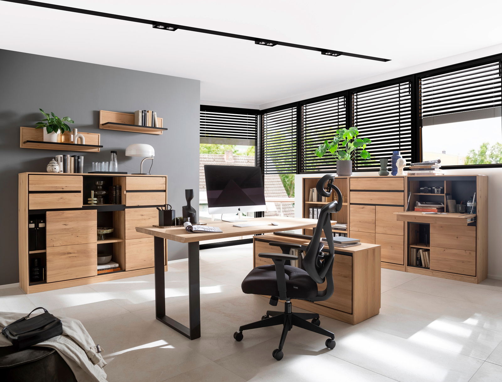 Moderne Büroumgebung mit einem Schreibtisch in der Mitte, umgeben von Holzregalen und Kommoden. Perspektive von vorne mit Blick auf den Schreibtisch und die Regale im Hintergrund.